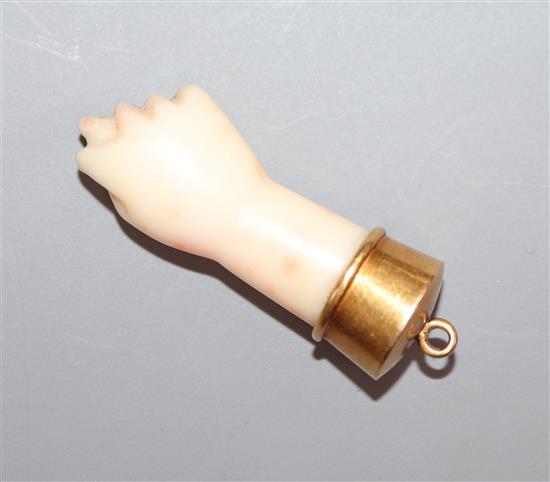 A yellow metal mounted coral pendant, modelled as a closed fist with protruding thumb, overall 38mm.